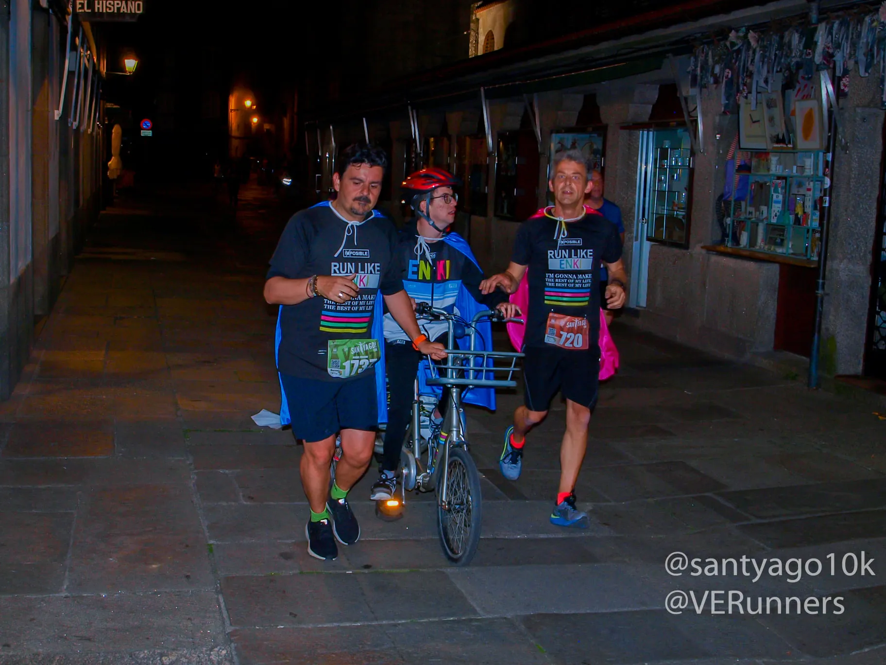 Wheelchair racer accompanied by two runners demonstrating inclusive racing through night streets
